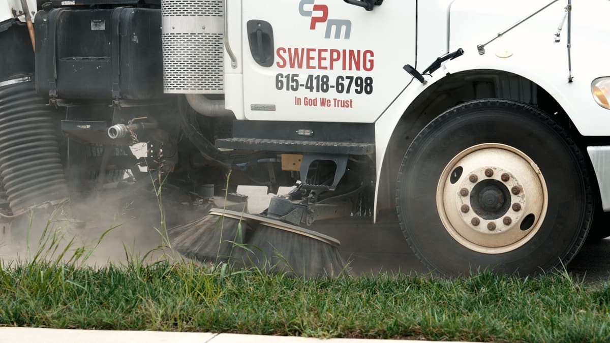 Side of a CPM Sweeping truck with the gutter broom down